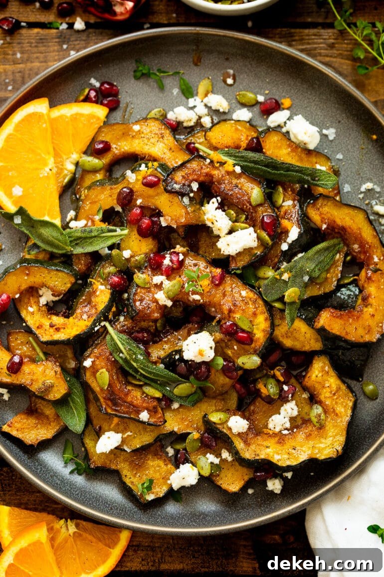 a photo of slices of roasted acorn squash topped with pomegranate seeds, feta, fried fresh sage, toasted pepitas, and fresh thyme.