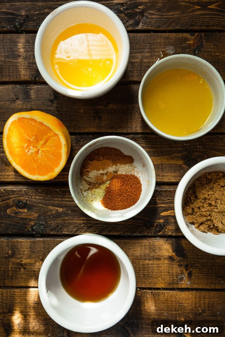 a photo of all the seasonings for holiday acorn squash in separate small bowls and a half an orange