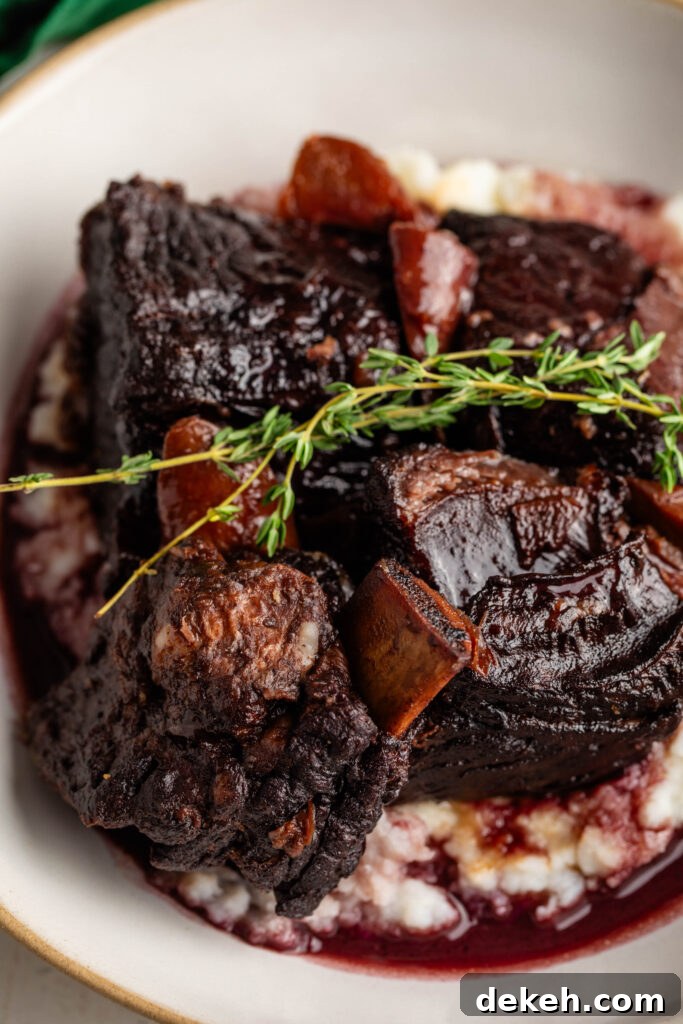 braised beef short ribs over a bed of mashed potatoes topped with thyme sprigs.