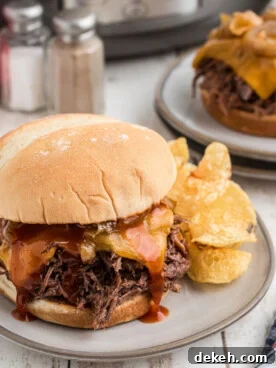 two plated slow cooker arby's beef and cheddar sandwiches.