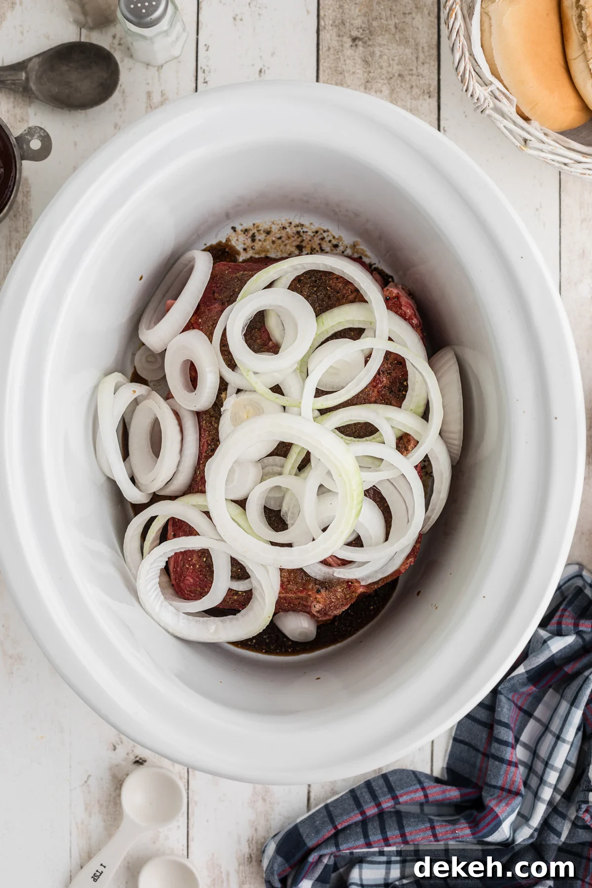 onions added on top of a chuck roast in a crockpot.
