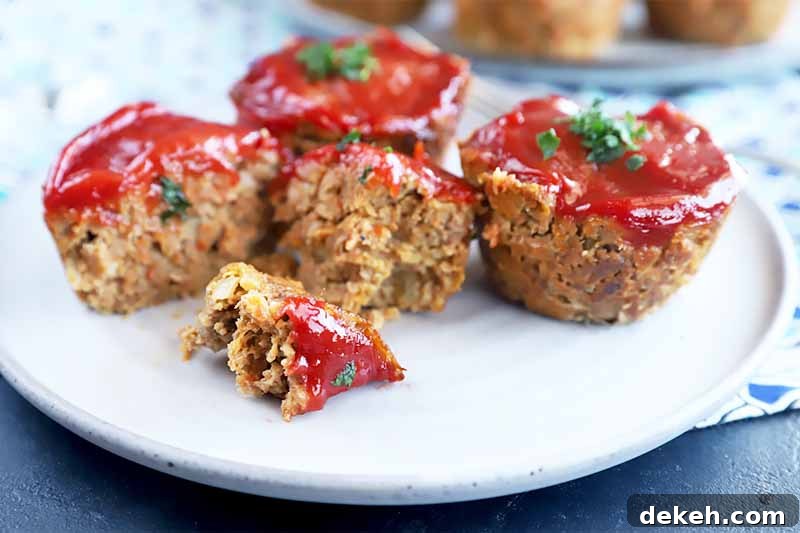 Horizontal image of a plate with individual ground beef rounds topped with ketchup, with one chopped in half.