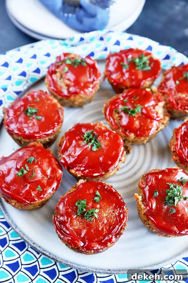 Vertical image of a white plate with scattered individual portions of ketchup-topped round appetizers.