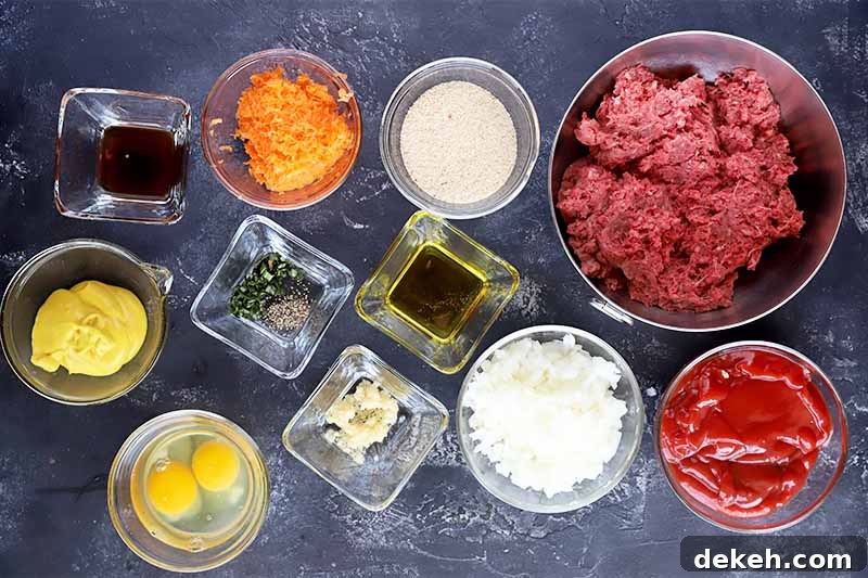 Horizontal image of assorted vegetables, seasonings, eggs and ground beef in various glass bowls on a gray surface.