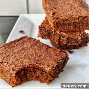 A stack of sliced brownies, one with a bite out of it.