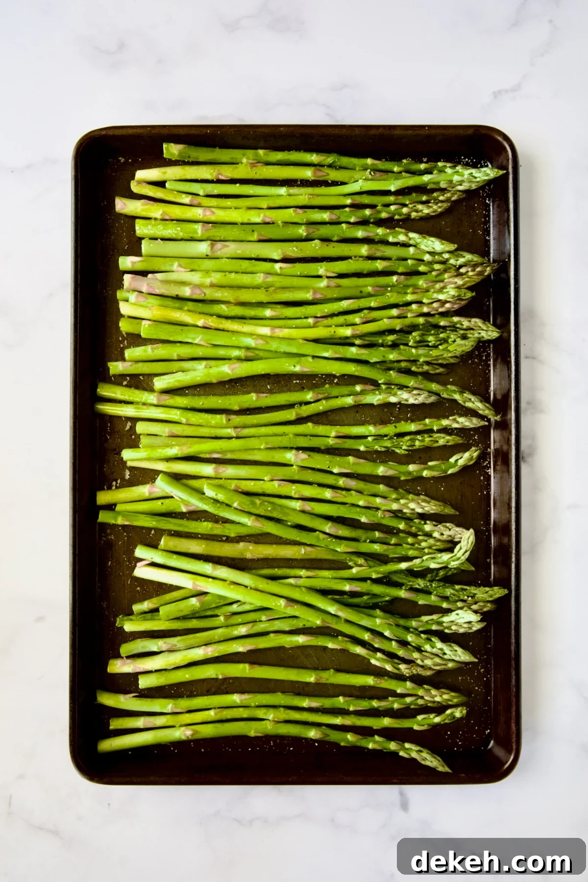 Asparagus on rimmed baking sheet before being roasted.
