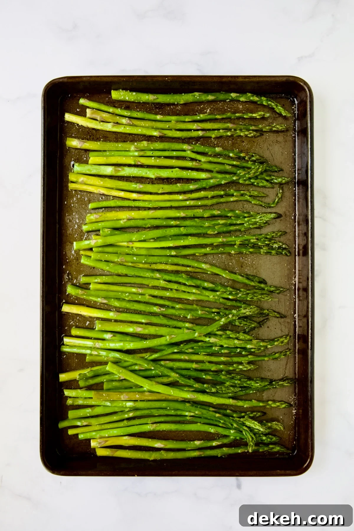 Roasted asparagus on rimmed baking sheet.