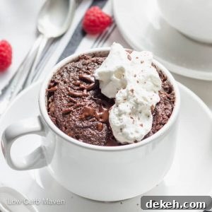 Keto chocolate cake in a cup with melted chocolate, whipped cream, and raspberries.