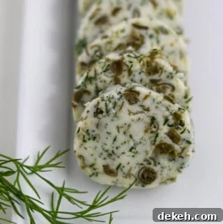 Close up of round of dill caper butter on a plate next to a sprig of dill.