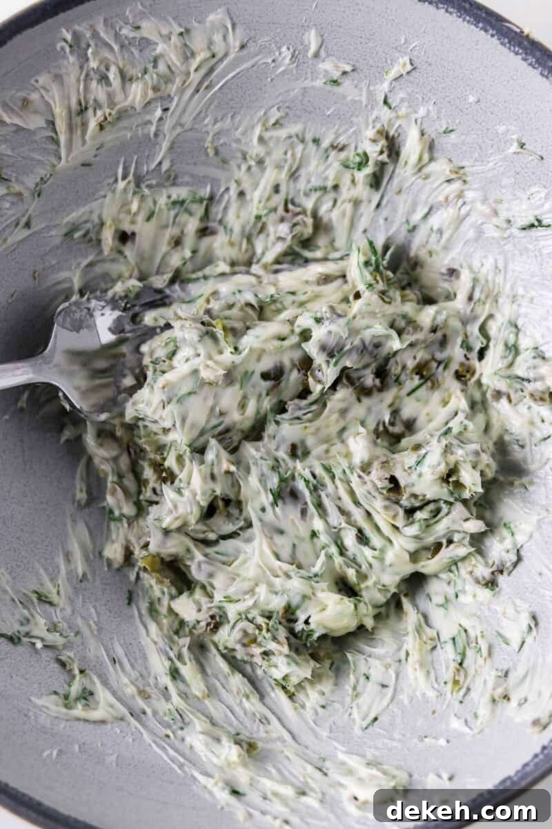 Dill Caper Butter being stirred with a fork in a bowl.
