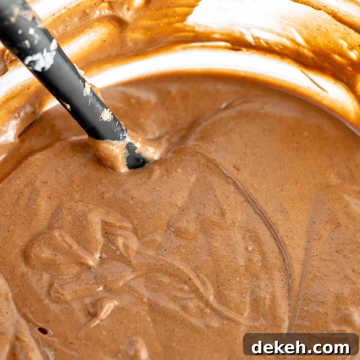 Chocolate cake batter in a mixing bowl with a black spatula sticking out.