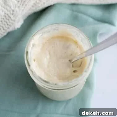 Jar of active sourdough starter with a spoon showing a smooth, bubbly texture.