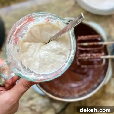 Measuring sourdough discard in a jar over a mixing bowl for adding to a recipe.
