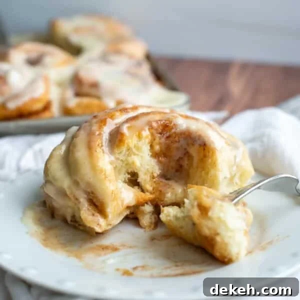 Replace Commercial Yeast with a Sourdough Starter 7 Sourdough Cinnamon roll on a plate with the center of the roll on a fork.