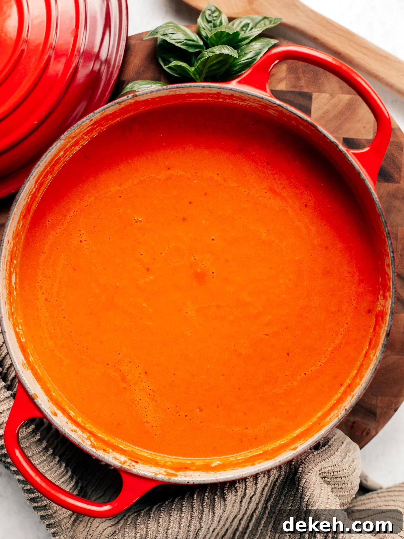 Creamy Homemade Tomato Soup Recipe with Basil and Garlic 2 Big pot of tomato soup on a wooden cutting board.