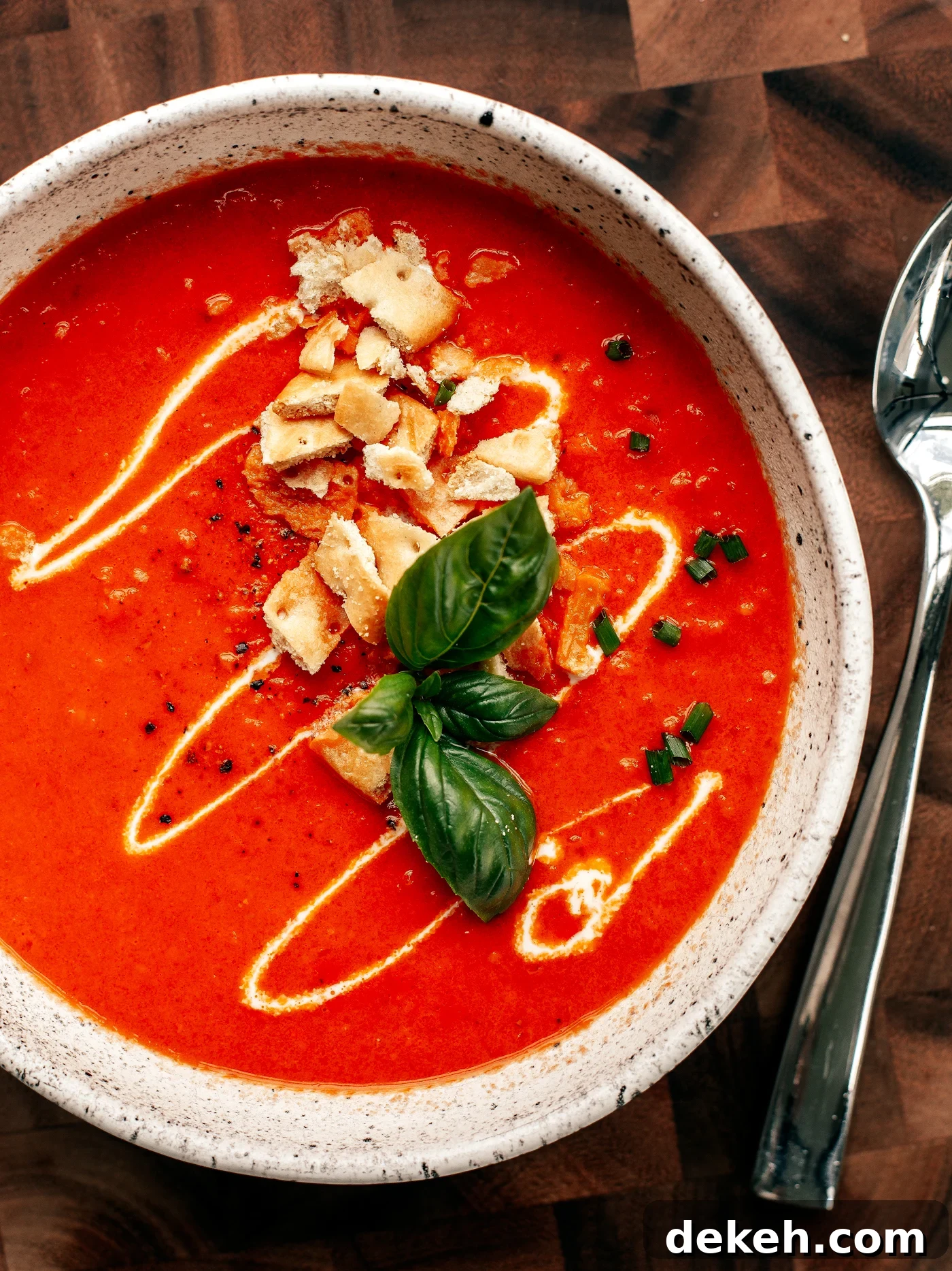 Creamy Homemade Tomato Soup Recipe with Basil and Garlic 7 Bowl of tomato soup with cream drizzle, crushed crackers, and basil leaves.