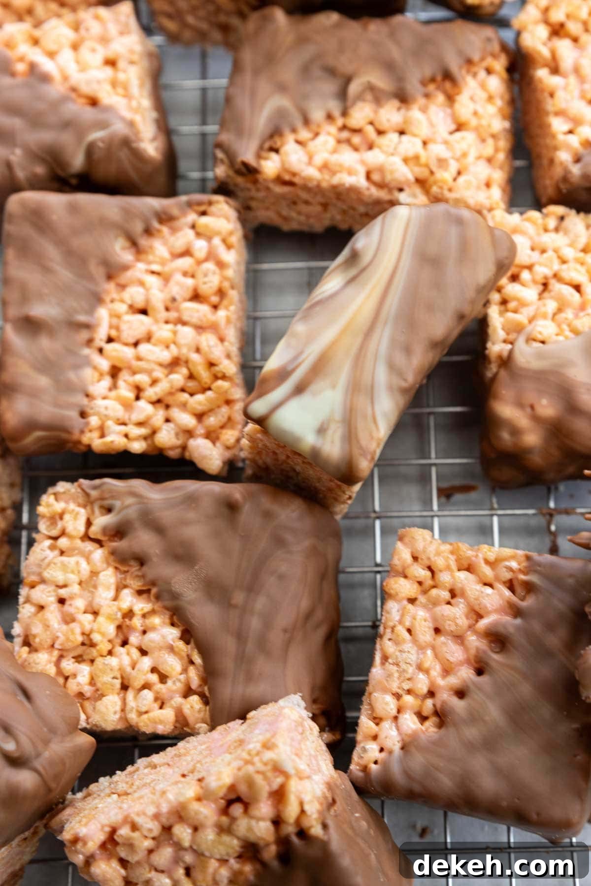 No-Bake Peanut Butter Crunch Bars — 6 Ingredients 11 Overhead view of square rice krispie bars half dipped in swirled white and milk chocolate, all on a cooking rack.