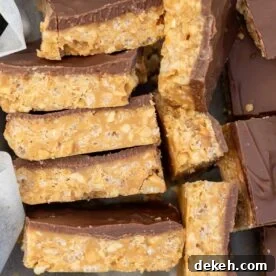 No-Bake Peanut Butter Crunch Bars — 6 Ingredients 12 A closeup of a stack of peanut butter chocolate crunch bars on their sides in a lined baking pan.