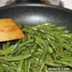 Sautéed seasoned green beans in a black frypan