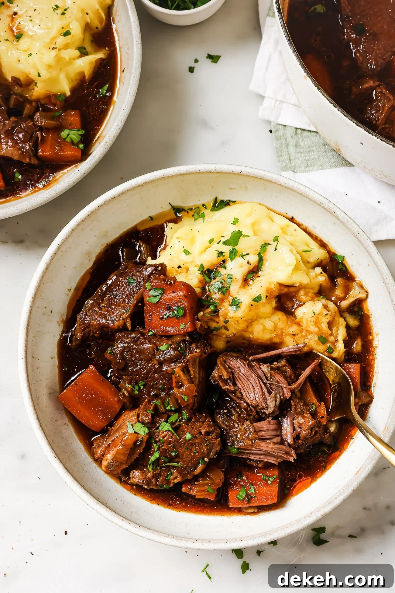 Tender Guinness-Braised Short Ribs 8 Guinness braised short ribs over mashed potatoes in a white bowl.