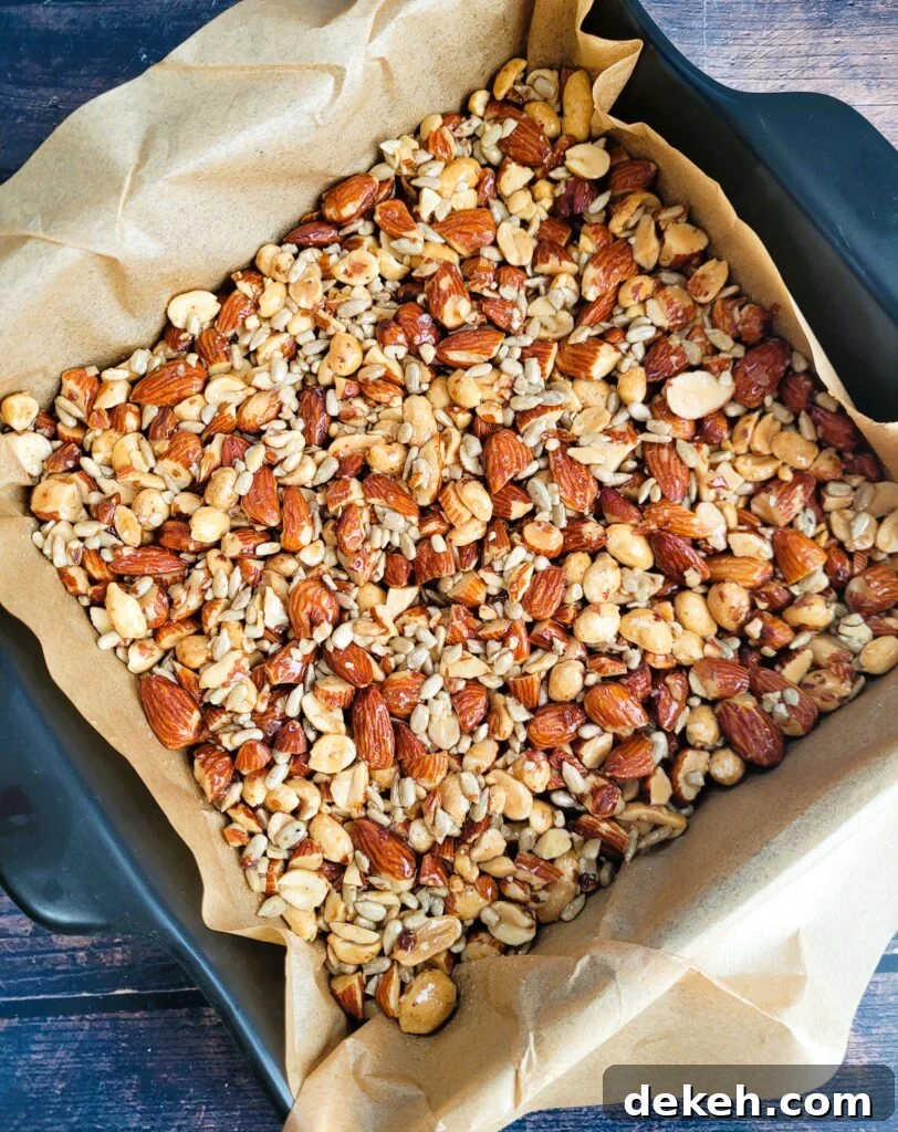 Crunchy Homemade Nut Bars: Step-by-Step Recipe 7 Pressing nut mixture firmly into parchment-lined pan for crunchy snack bars.