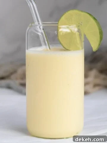 pina colada smoothie with a lime wedge in a glass