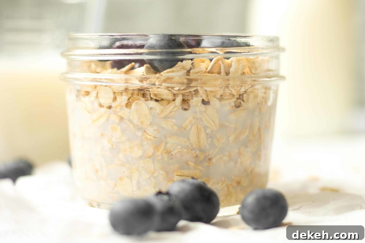 8oz glass mason jar with blueberry overnight oats and whole blueberries on the side
