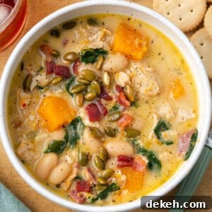 Creamy Chicken and Butternut Squash Soup Recipe 18 A bowl of chicken butternut squash soup topped with roasted pepitas and bacon pieces.