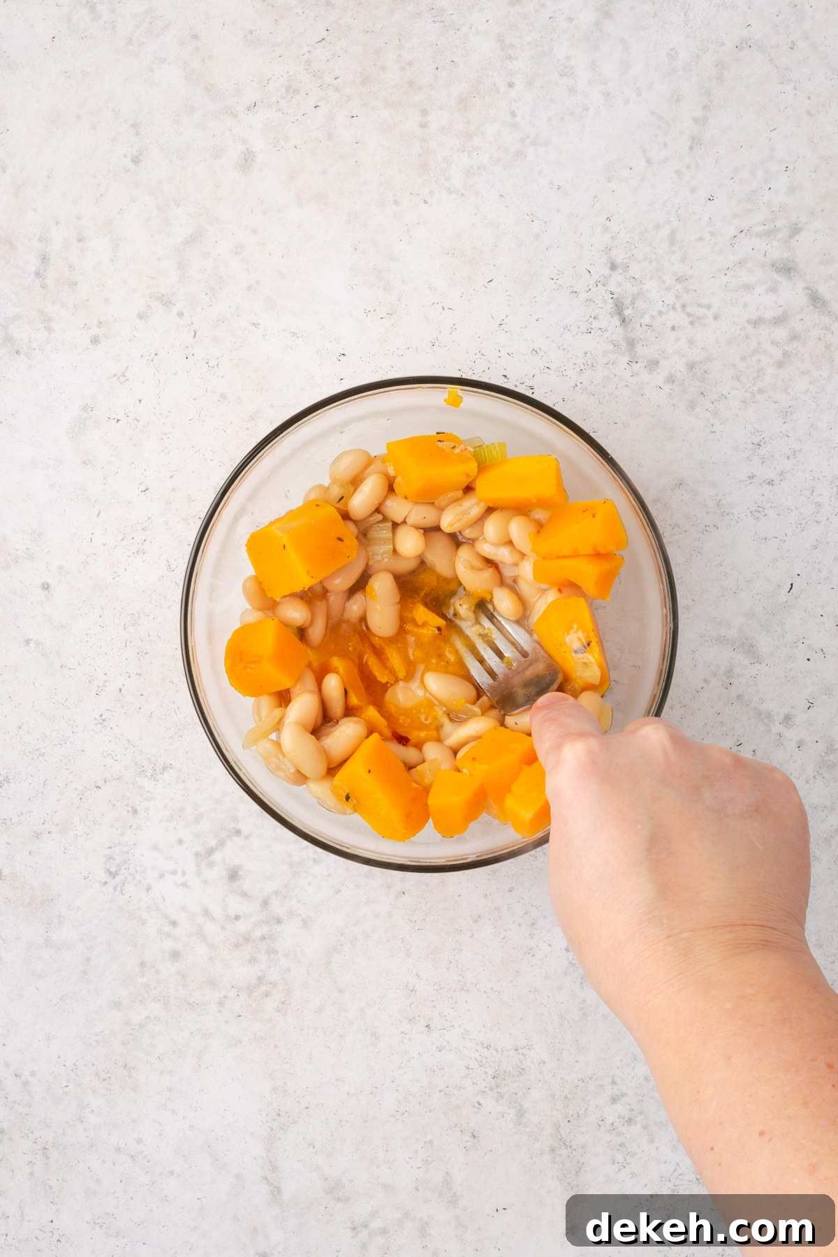 Creamy Chicken and Butternut Squash Soup Recipe 8 White beans and cooked squash being mashed in a small bowl.