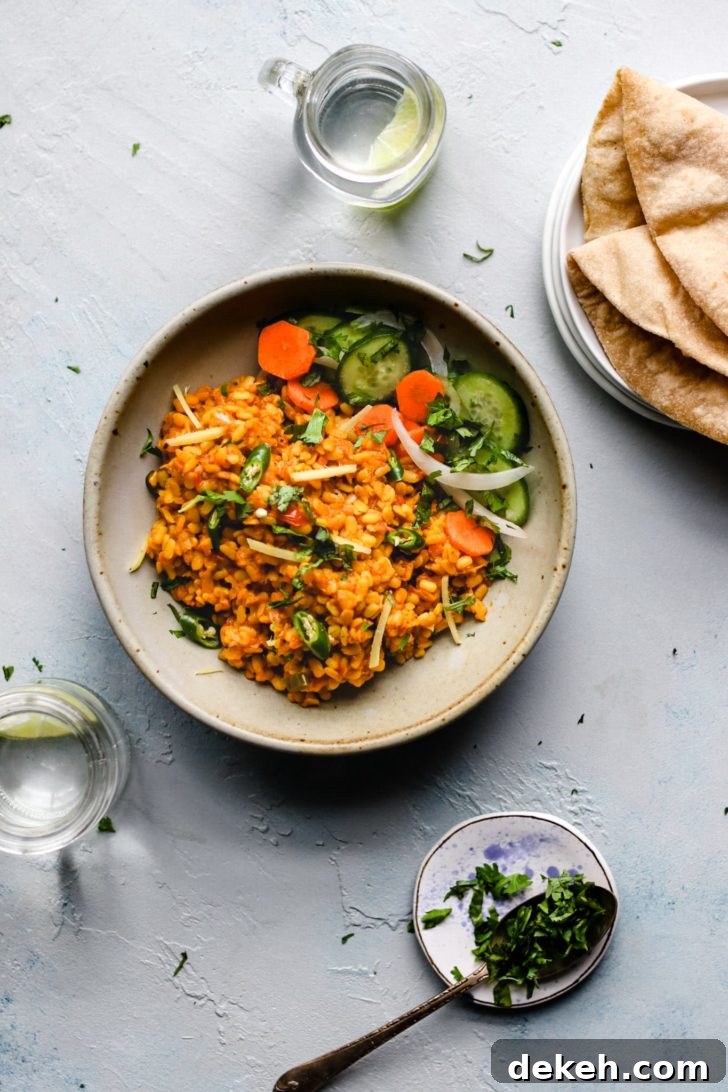 Authentic Pakistani Maash (Urad) Dal Recipe 2 Plate of Maash Ki Dal (Urad Dal) with cucumbers and carrots garnished with sliced onions, green chilies and cilantro beside a plate of roti.
