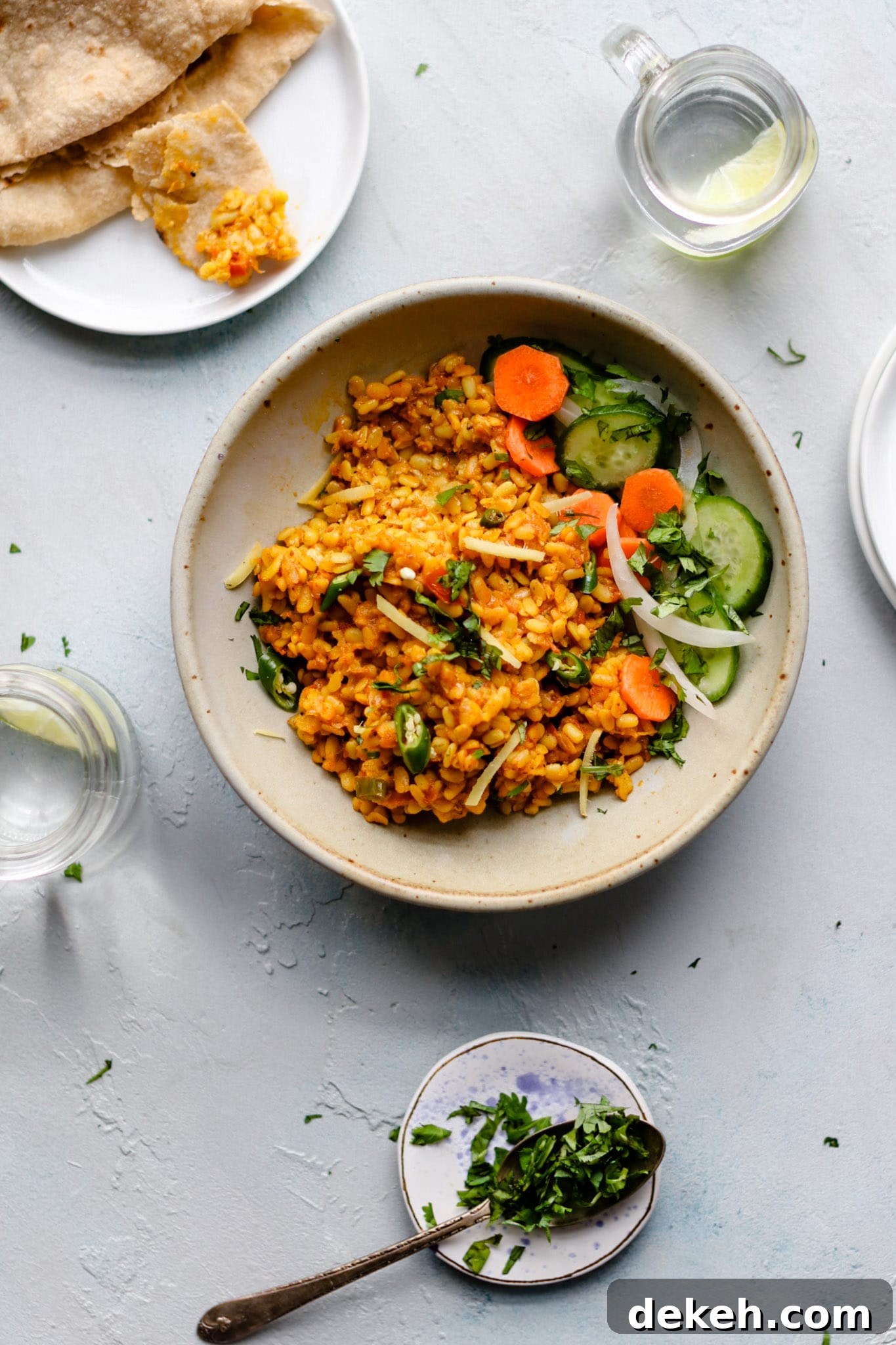 Authentic Pakistani Maash (Urad) Dal Recipe 7 Top view of a bowl of Maash ki Dal (Urad Dal) with cucumbers and carrots garnished with sliced onions, green chilies and cilantro.